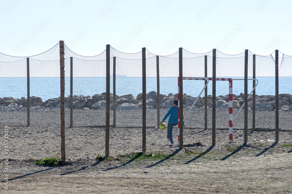 Niño jugando al fútbol de portero en la playa / Boy playing goalkeeper football on the beach
