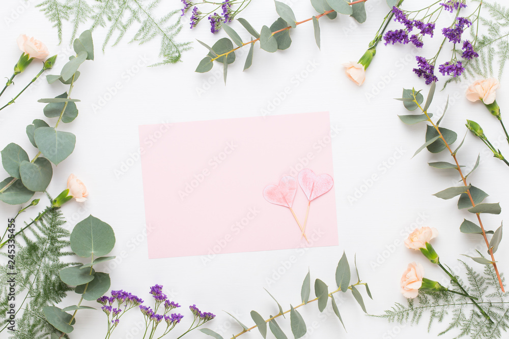 Fototapeta premium Flowers composition. Paper blank, carnation flowers, eucalyptus branches on pastel background. Flat lay, top view, copy spaceFlat lay stiil life.