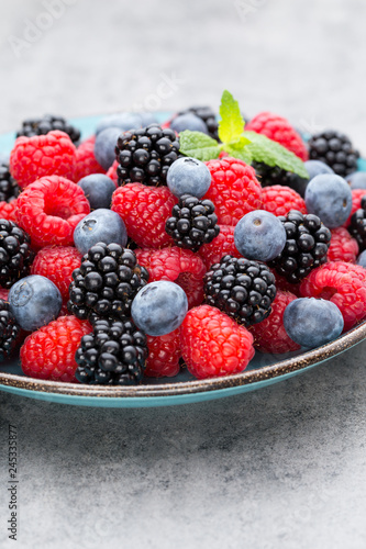 Fresh berry salad on blue dishes. Vintage wooden background.