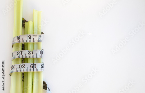 celery wrapped with measuring tape on white background.losing weight concept.Vegan food.