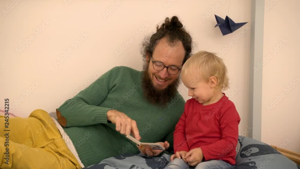 Father reading book to Infant son at children room. Father reading book to Infant son at children room.