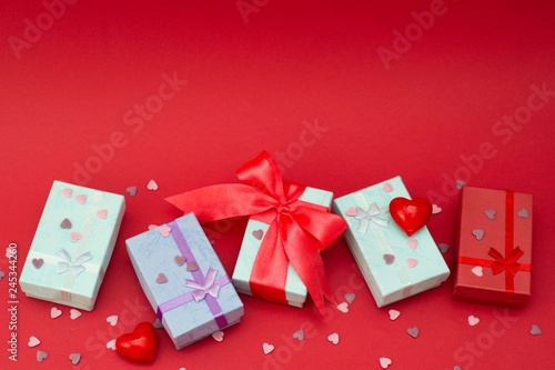 Many colorful gift boxes on red background. Valentine's day, mother's Day, birthday or party concept. Hearts decorations. Copy space. photo