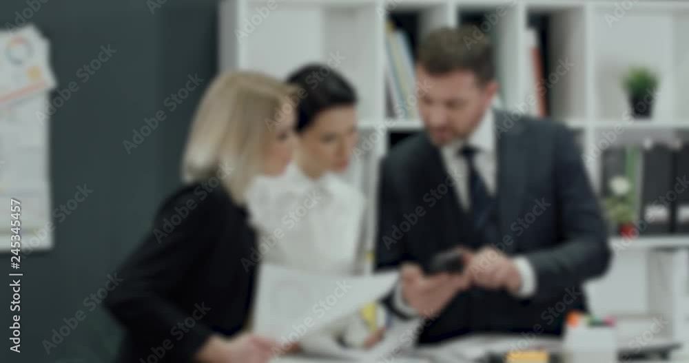 Blurred view, businessman gives instructions to girls managers, teamwork in office interior. Blurred view, businessman gives instructions to girls managers, teamwork in office interior.
