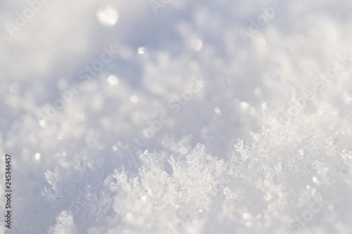 White snow flakes in close up glittering in sunlight, winter background.