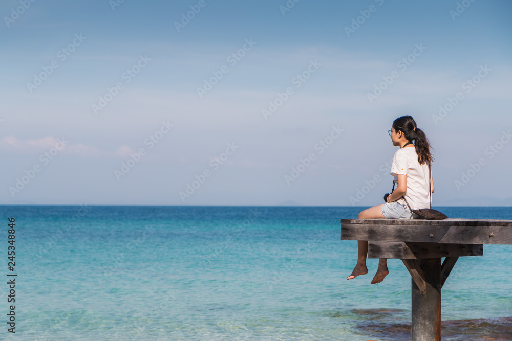 Traveler woman setting and feeling happy on the bridge at the summer sea tropical island background.Concept of relax on vacation holidays.