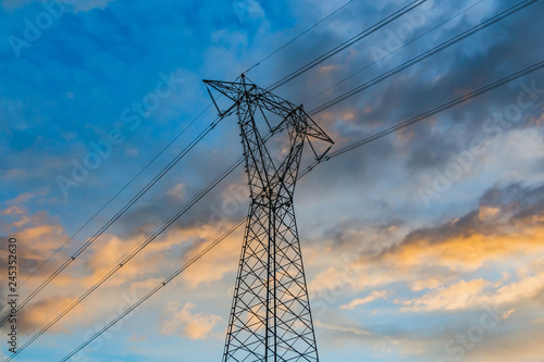 A power line on the blue sky background with pink clouds at the sunset