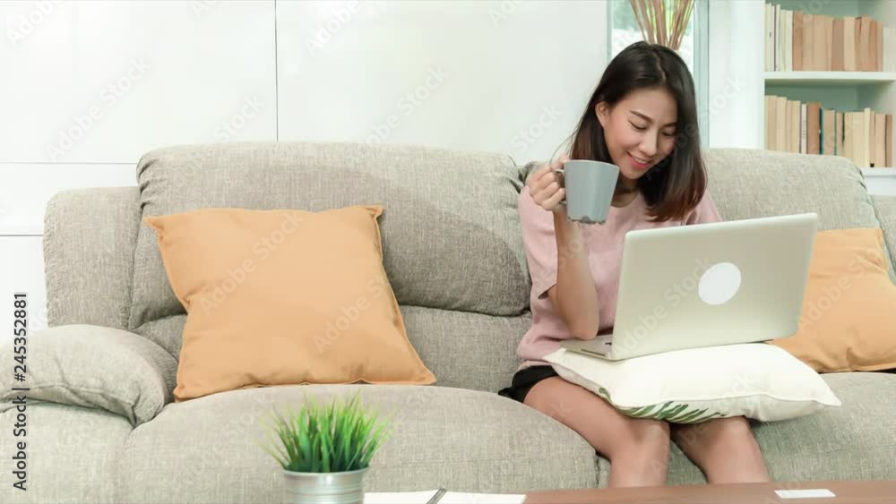 attractive young Asian woman drinking coffee during happy working with notebook computer sitting on sofa in beautigul decoration living room, happy lifestyle, RAW, UHD, 4K, 23.98, Proresss444 attractive young Asian woman drinking coffee during happy working with notebook computer sitting on sofa in beautigul decoration living room, happy lifestyle, RAW, UHD, 4K, 23.98, Proresss444
