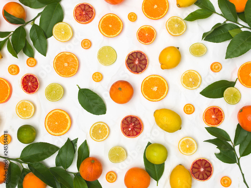 many different fresh citrus fruits on white crumpled paper background