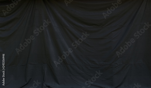 Background image of black canvas curtain hanging with wrinkles