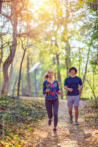 Cardio exercise - couple enjoying in a healthy lifestyle while jogging along a forest,.