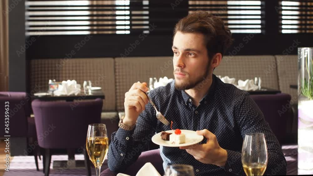 Elegant pensive guy sitting and eating yummy cake at the cafe, free time, thoughtful man enjoys dessert indoors Elegant pensive guy sitting and eating yummy cake at the cafe, free time, thoughtful man enjoys dessert indoors