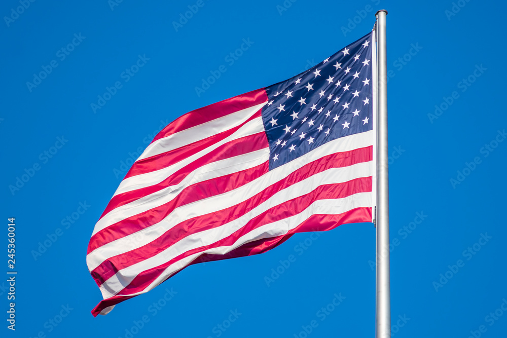 Flag of United States of America waving in wind, against clear sky Flag of United States of America waving in wind, against clear sky