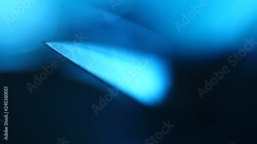 Sharp point of a knife reveals out of the darkness.