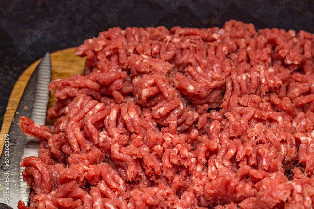 Close up of lean minced beef and sharp knife on a wooden chopping board Close up of lean minced beef and sharp knife on a wooden chopping board
