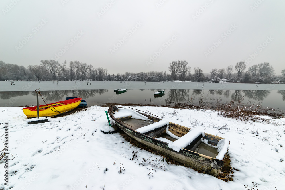 Naklejka premium Beautiful frozen river. A boats covered with snow.