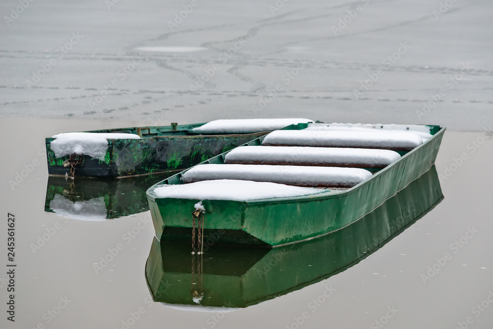 Naklejka premium Beautiful frozen river. A boats covered with snow.