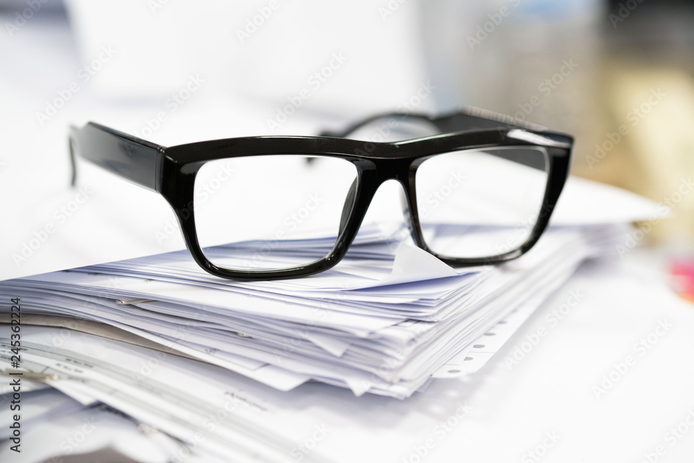Paper heap from hard work is under black glass Paper heap from hard work is under black glass