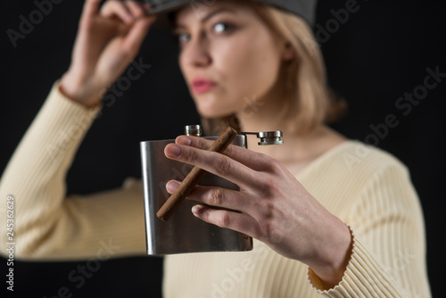 Time to enjoy. Cigar and hip flask in ladys hand. Sensual woman hold cigar and alcohol container. Addicted woman with sexy look. Unhealthy lifestyle and bad habits. Alcohol and tobacco addiction