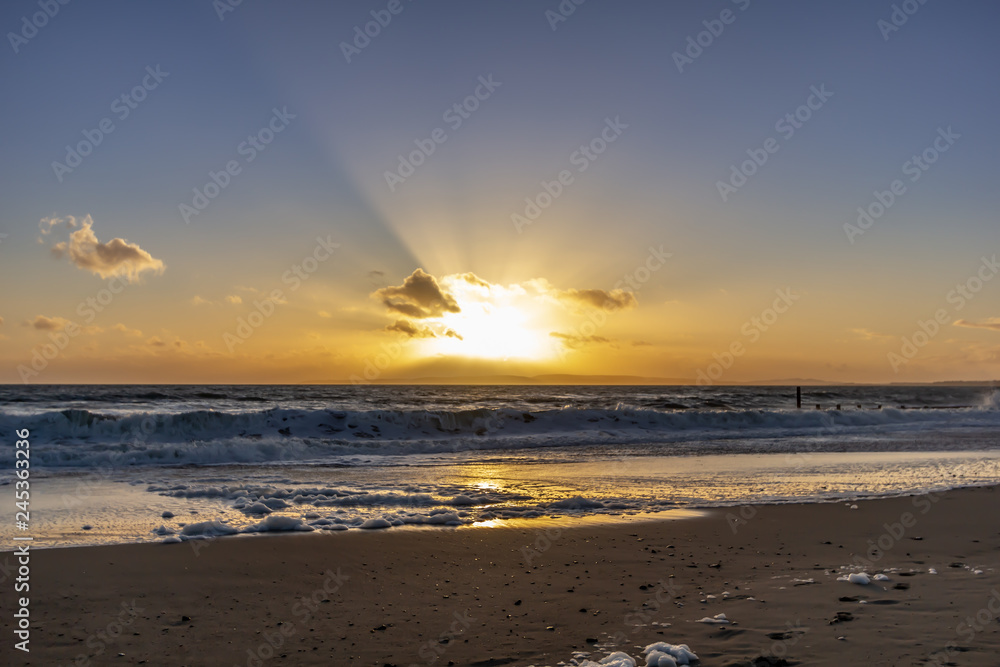 Sunset over the sea with crashing waves and white clouds Sunset over the sea with crashing waves and white clouds
