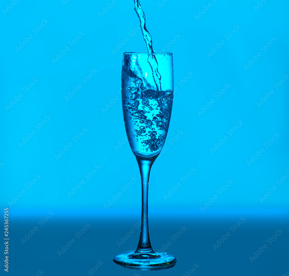Splashes and bubbles of water. Glass on a blue background. Minimal night party life concept Splashes and bubbles of water. Glass on a blue background. Minimal night party life concept
