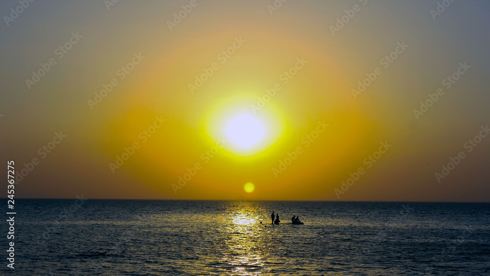yellow sunset on the sea and black silhouettes of people against the sun