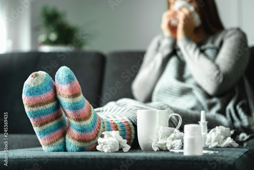 Photo Sick woman with flu, cold, fever and cough sitting on couch at home
