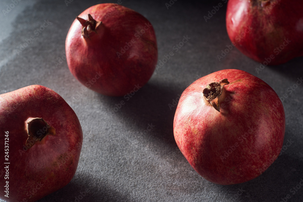 Studio shot of fresh pomegranates on black surface Studio shot of fresh pomegranates on black surface