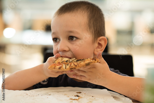 cute little boy eating pizza 