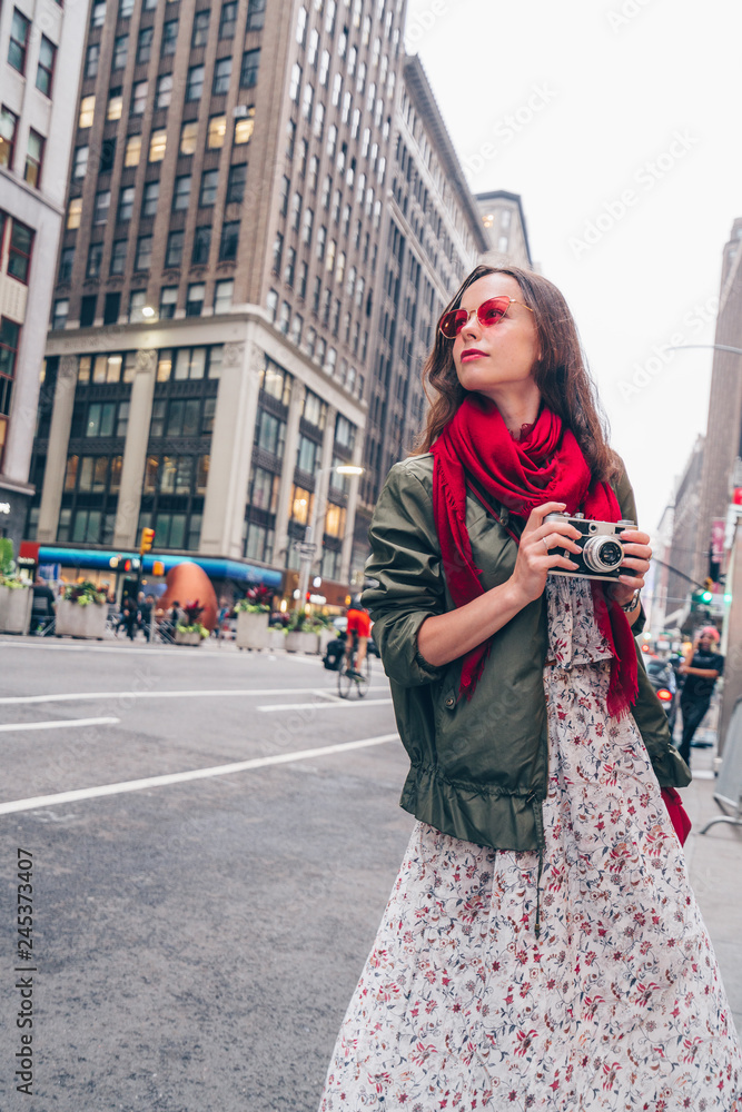 Fototapeta premium Attractive girl with a retro camera in the city