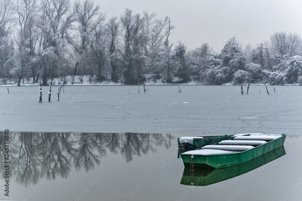 Naklejka premium Beautiful frozen river. A boats covered with snow.