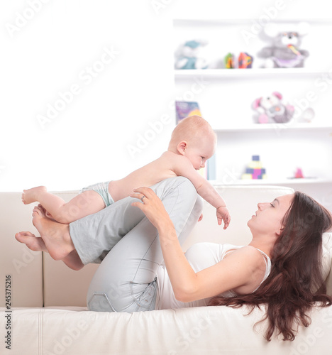 young mom playing with a pretty baby on the couch