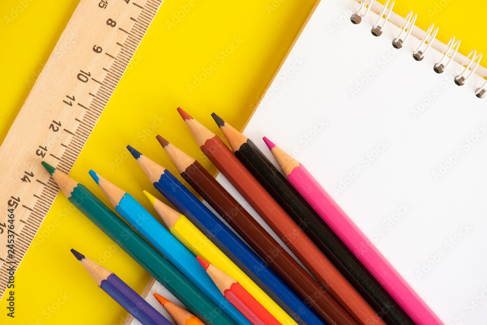 Color pencils, ruler and notepad, on the yellow background. Color pencils, ruler and notepad, on the yellow background.
