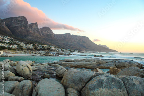 Beautiful sunset at Camps Bay, seen from the boulders on the shore in Cape Town, South Africa