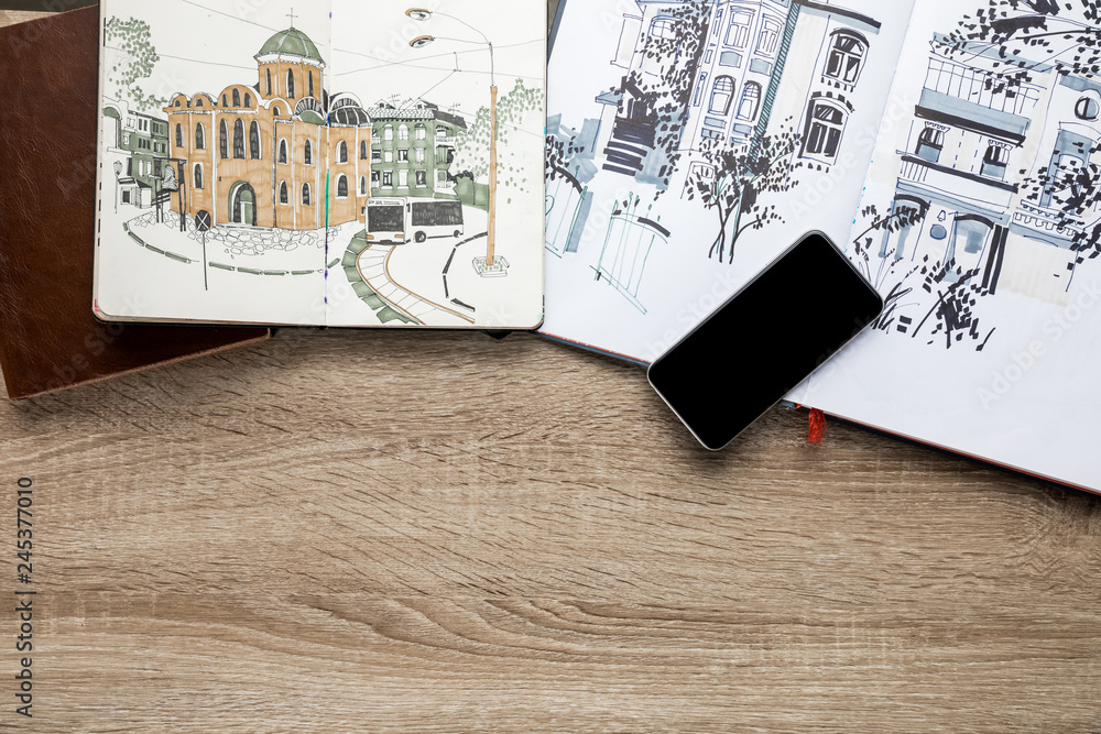 top view of drawings in albums and smartphone on wooden background