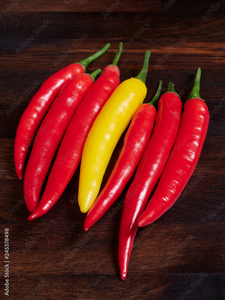 Red and yellow chilis on a dark rustic wooden oak board