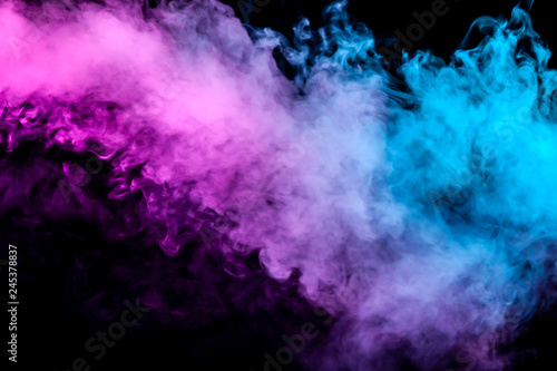 Translucent, thick smoke, illuminated by light against a dark background, divided into two colors: blue and purple, burns out, evaporating from a steam of vape.