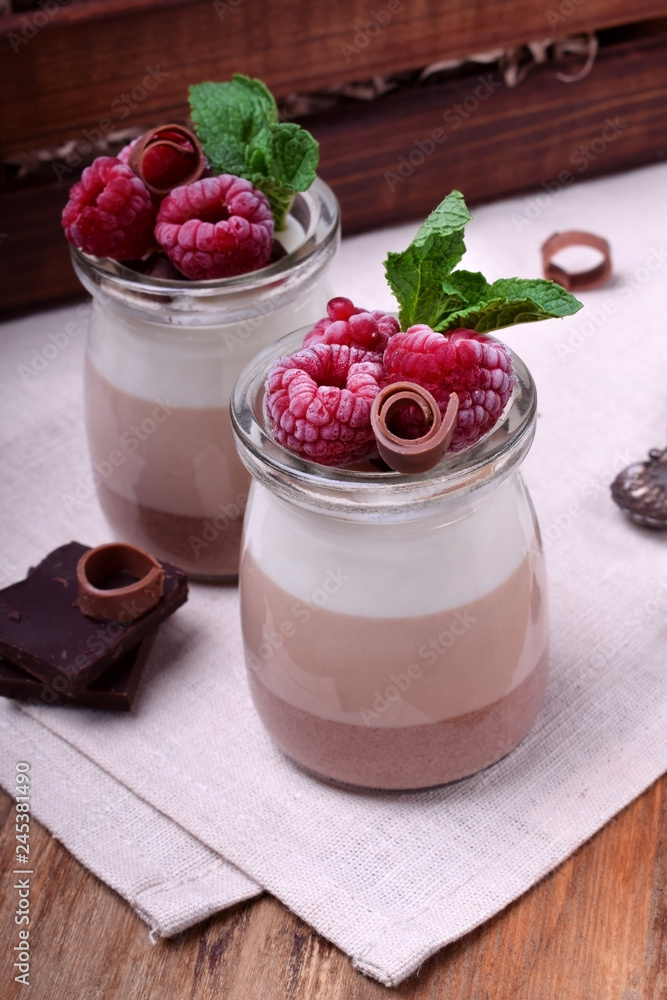 Three chocolate mousse dessert in a glass jar garnished with frozen raspberries Three chocolate mousse dessert in a glass jar garnished with frozen raspberries