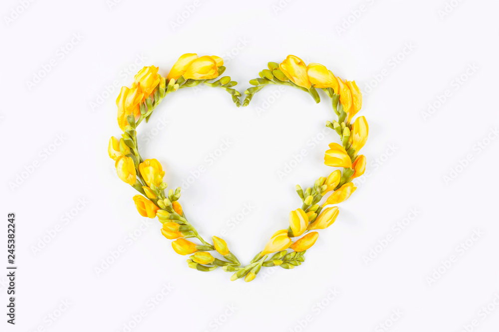 Obraz premium Heart of yellow flowers on white background. Flat lay, top view. Floral background. Flowers pattern texture. Valentine's background. Valentines Day and Mother Day background