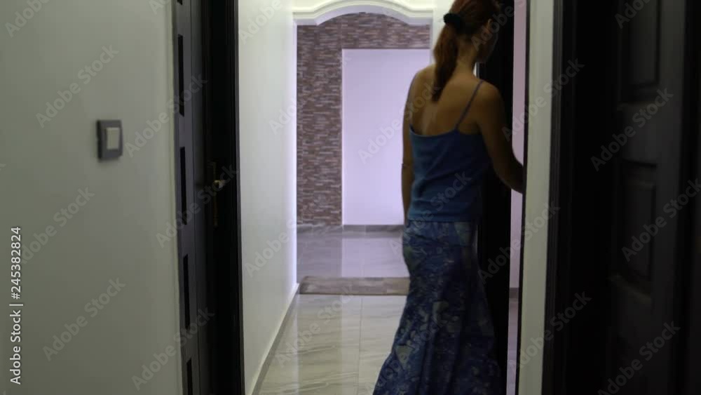 A woman walks down the corridor enters the room and closes the door. A woman walks down the corridor enters the room and closes the door.