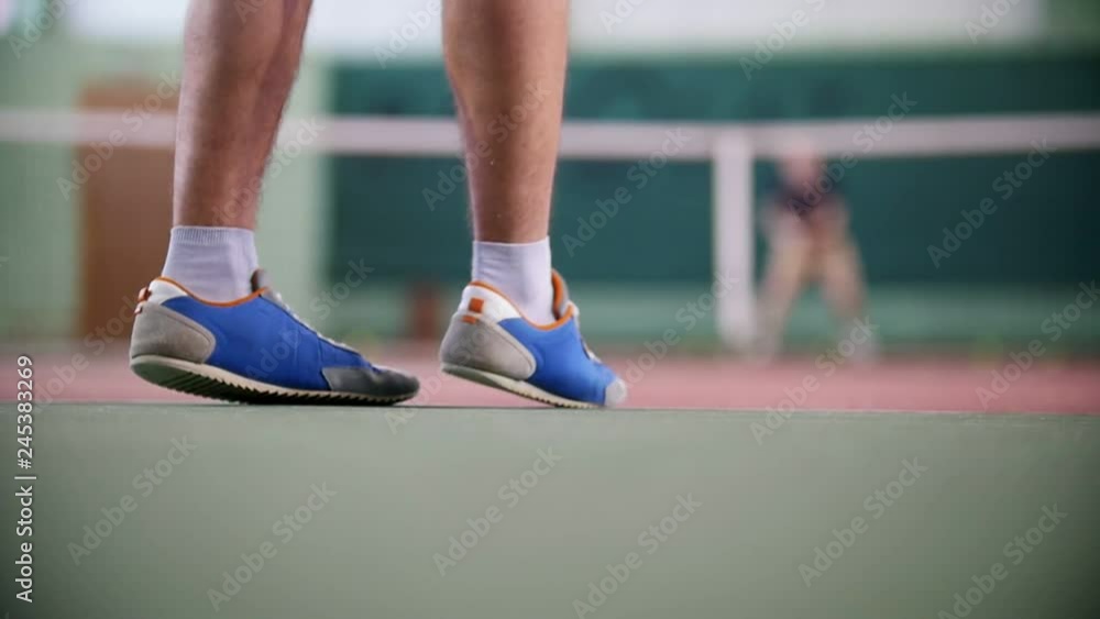 Training on the tennis court. Two young men playing tennis. Feet in focus Training on the tennis court. Two young men playing tennis. Feet in focus