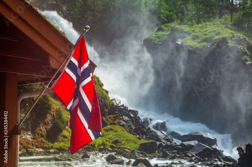 Norwegian flag against waterfall in Norway Scandinavia