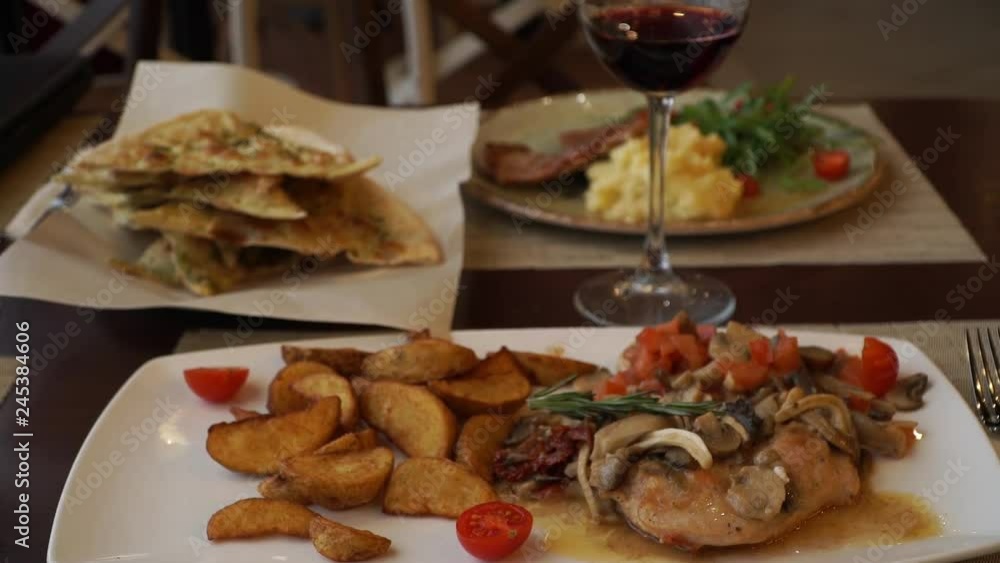 A dish in the restaurant chicken and potato slices with rasmarine sauce and cherry tomatoes. Focaccio with a glass of red wine A dish in the restaurant chicken and potato slices with rasmarine sauce and cherry tomatoes. Focaccio with a glass of red wine
