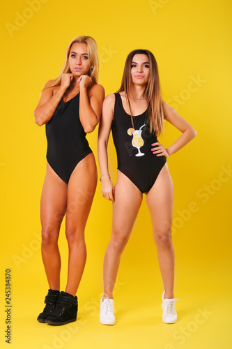 Two sexy model in black swimsuit on yellow background
