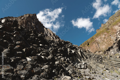 Wide angle view of a rocky slope on a sunny summer day. Structural hexagonal cliffs in the North Caucasus