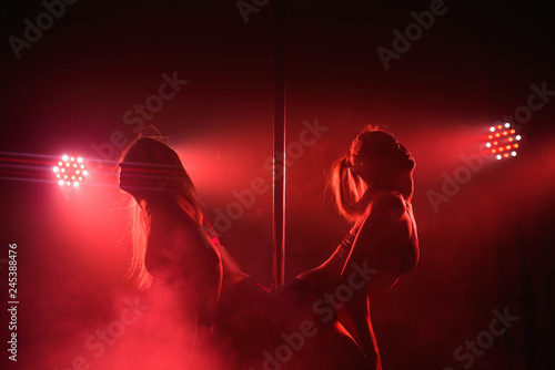 Obraz na płótnie Two young girls doing acrobatic tricks with a pole