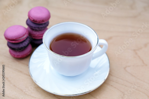 Cup of tea with saucer and macaroon on wooden background. Minimalism