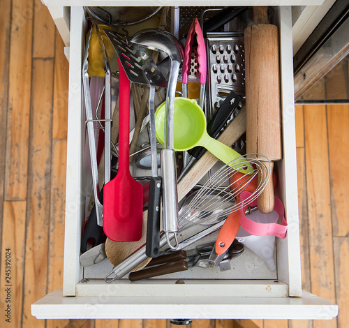 a kitchen drawer packed with utensils is shown