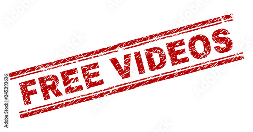 FREE VIDEOS seal print with grunge texture. Red vector rubber print of FREE VIDEOS tag with retro texture. Text label is placed between double parallel lines.