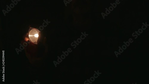 a man with an electric torch focuses towards the camera