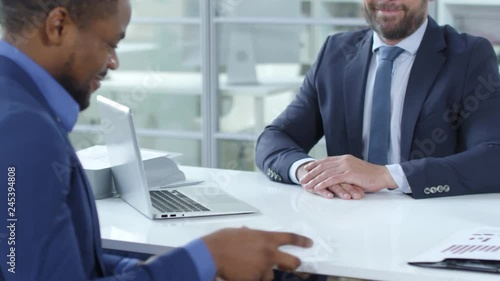 Wallpaper Mural Caucasian businessman in formal suit giving envelope with money to african american colleague; he opening it and counting banknotes under the table in the office Torontodigital.ca